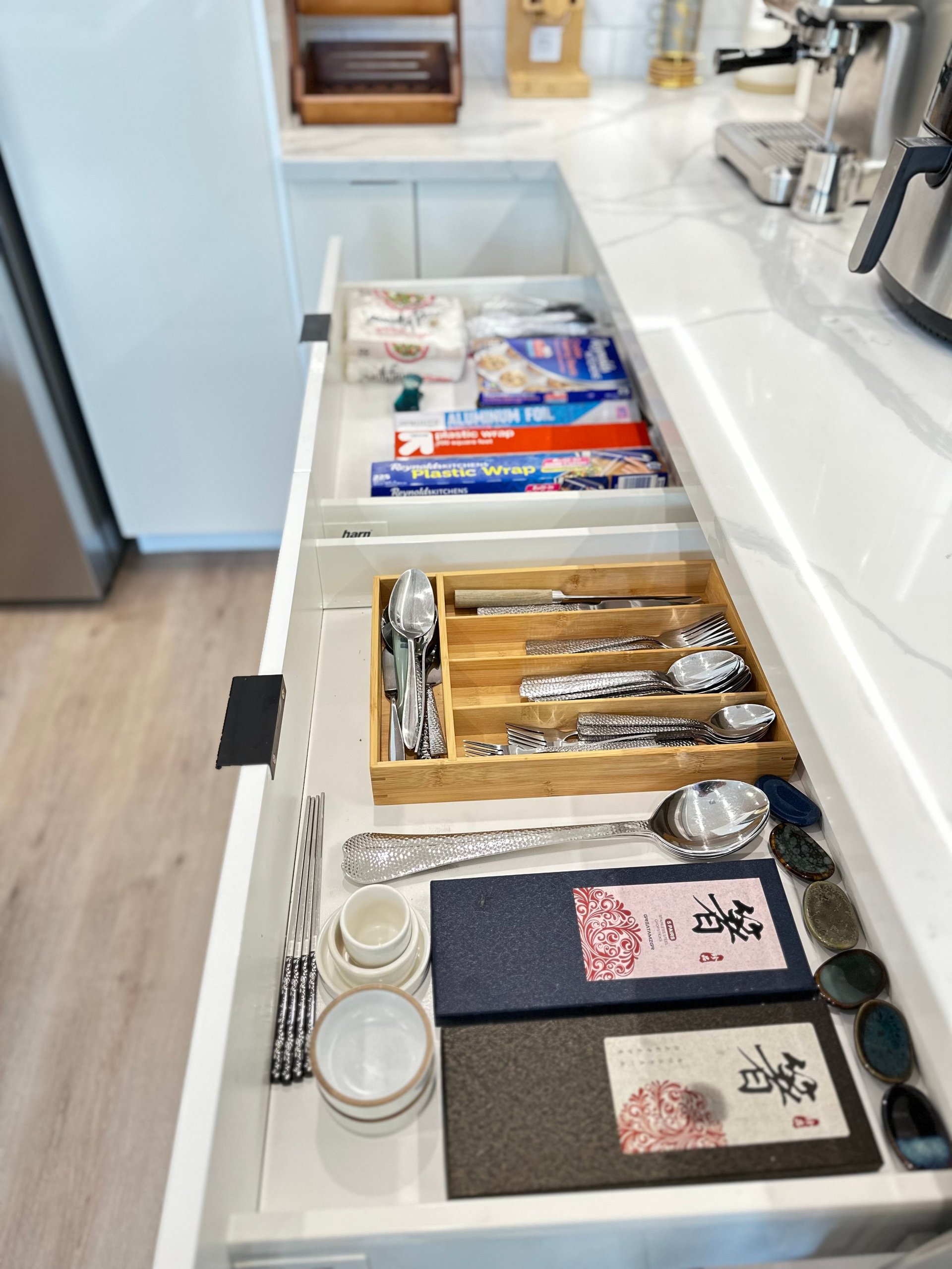 Organized kitchen drawer with utensils, wooden silverware organizer, food storage bags, and various kitchen items